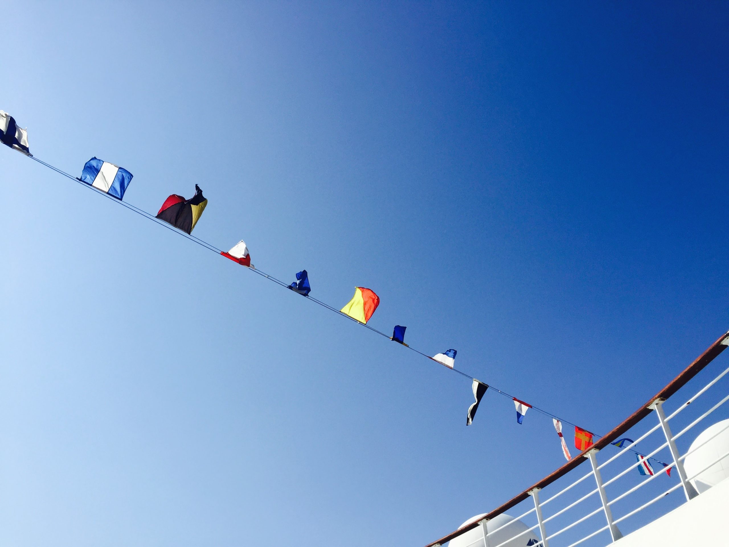 船のデッキから見た青空と国旗