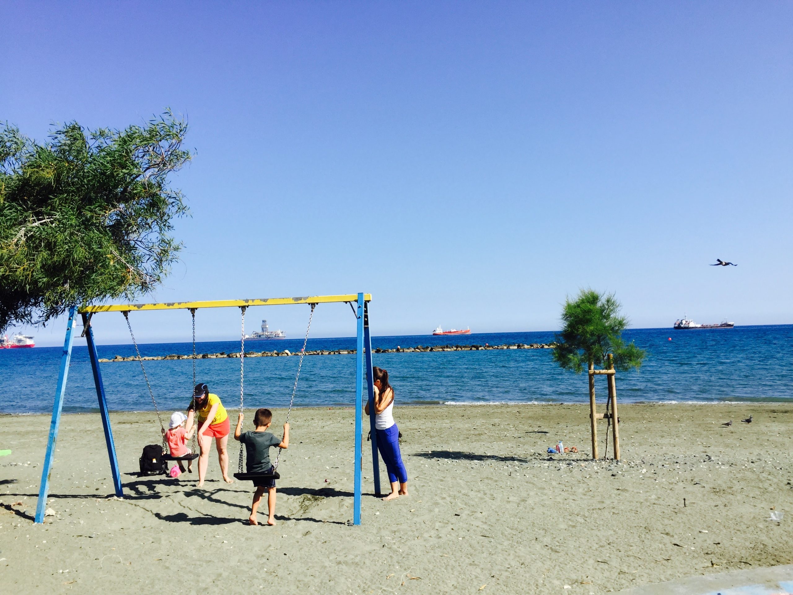 キプロスの海と砂浜にあるブランコで遊ぶ親子